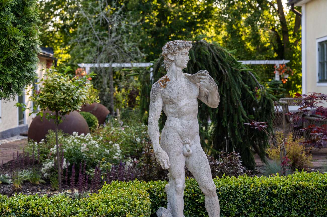 Davidstaty i trädgården omgiven av buxbom och blomsterrabatter