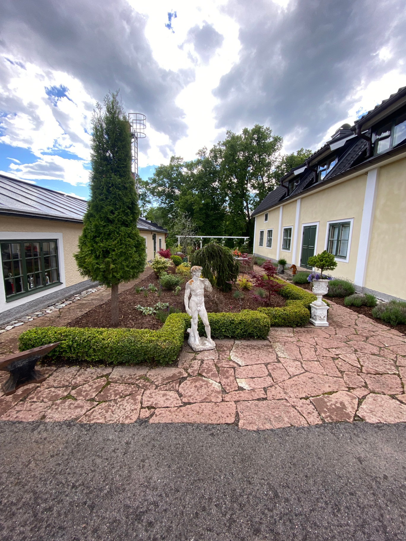 Innergård med staty, formklippta buxbomshäckar och stenläggning