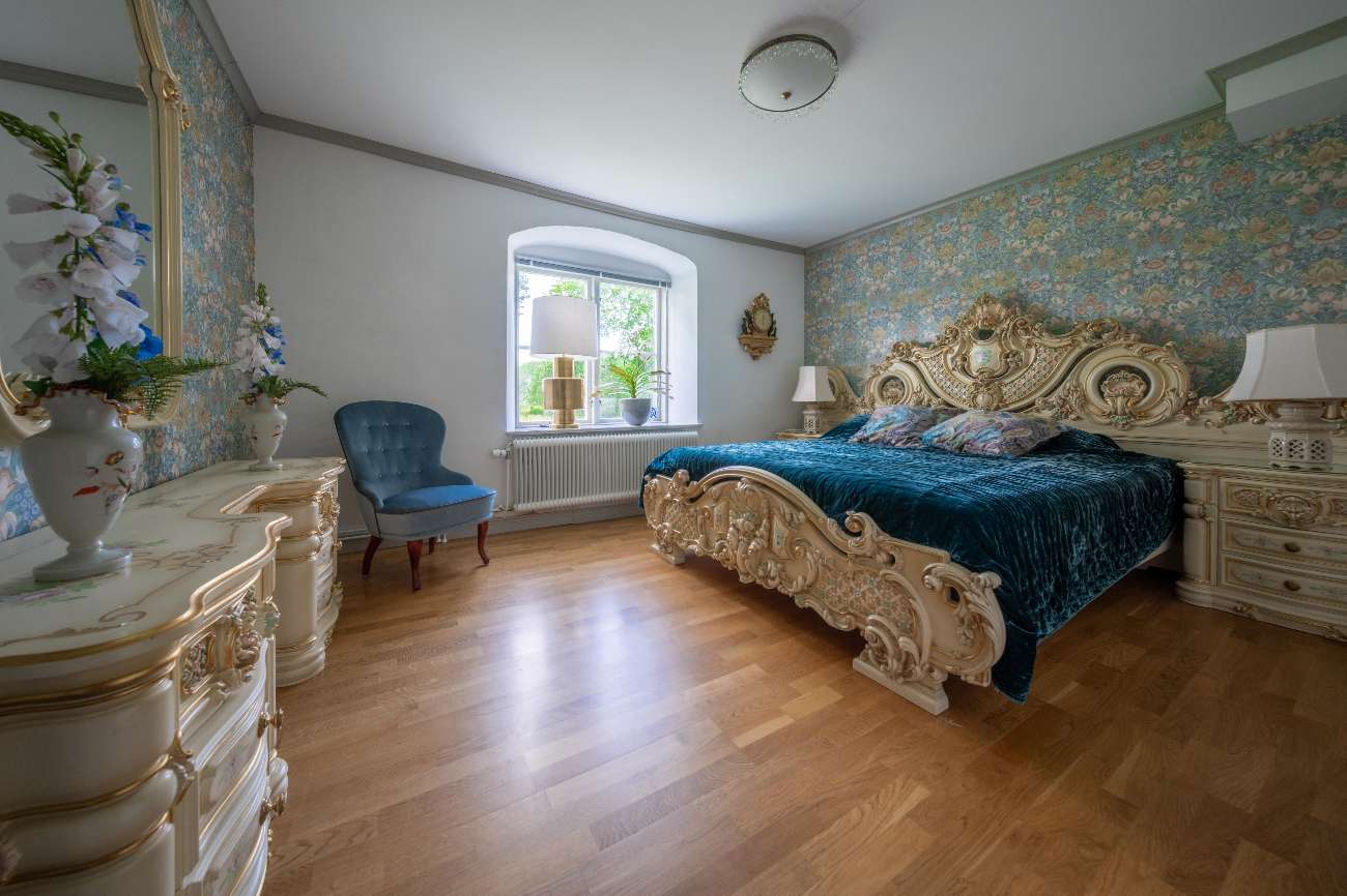 Italienska rummet med barockmöbler i vitt och guld, turkos sängöverkast och blommig tapet på Borggård Hälsocenter.