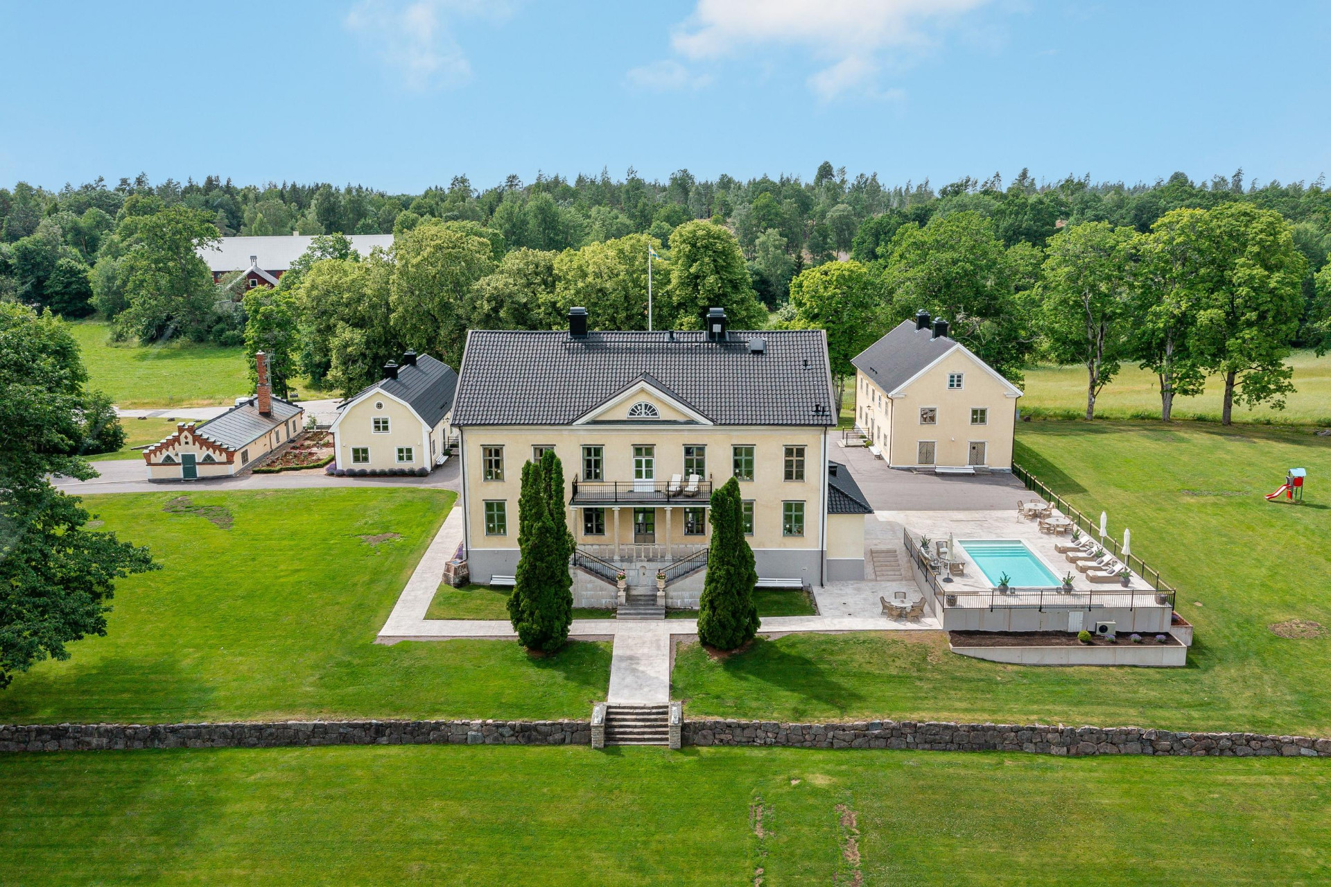 Flygbild över herrgården med pool och flygelbyggnader