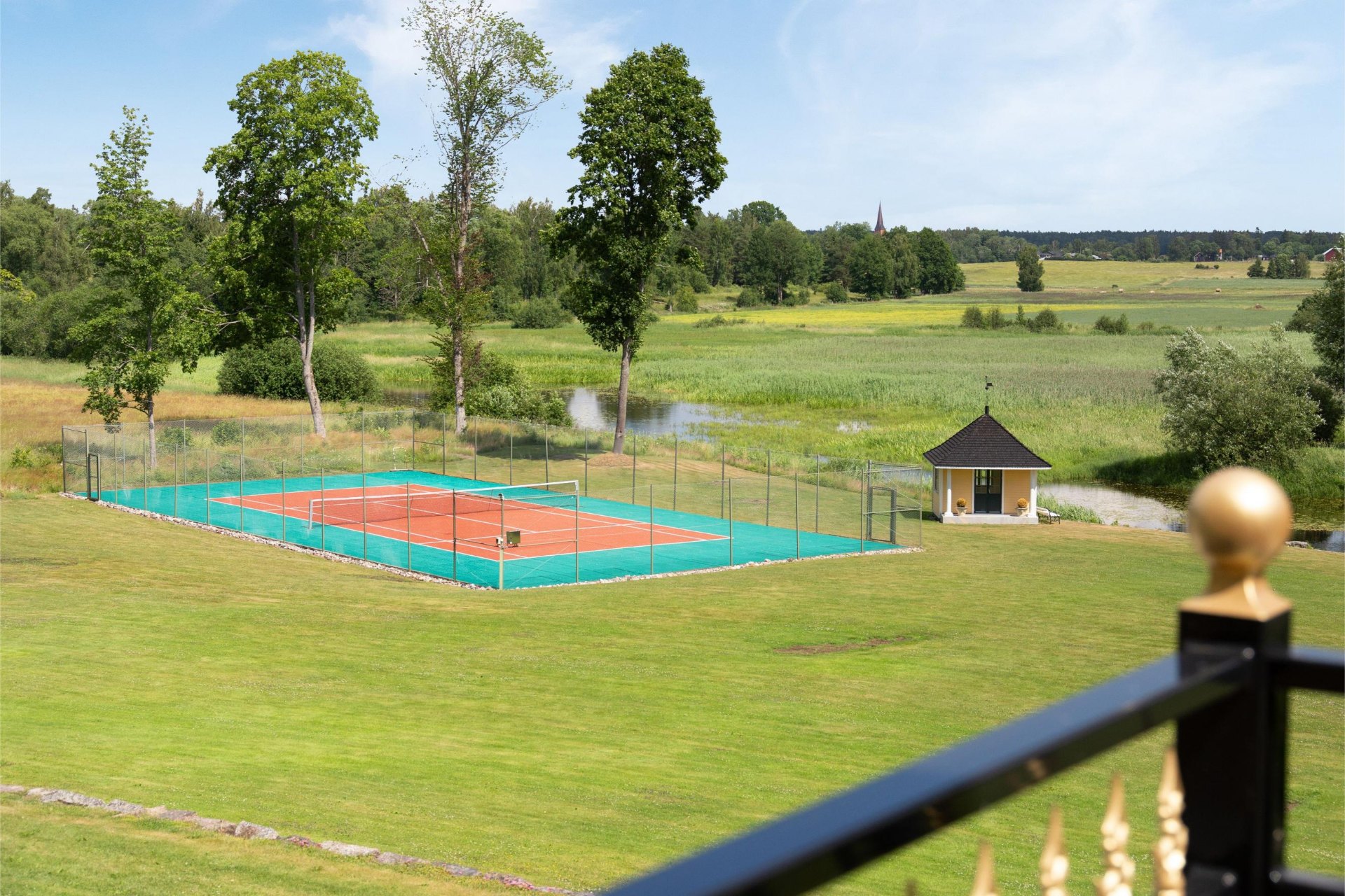 Tennisbana med paviljong och utsikt över ängarna